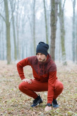 Genç adam ormanda soğuk bir kış günü koştuktan sonra dinleniyor..