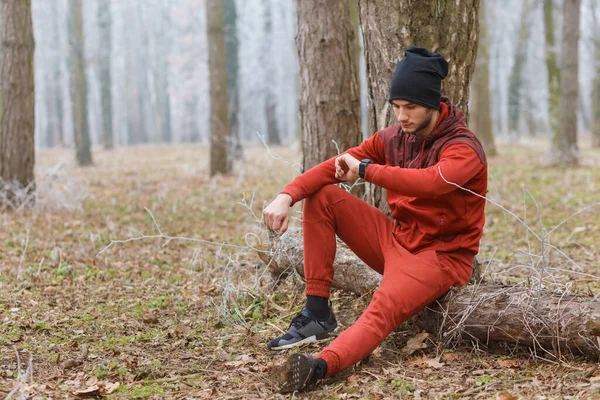 Genç adam ormanda soğuk bir kış günü koştuktan sonra dinleniyor..