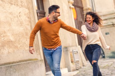 Mutlu çift, güneşli bir sonbahar gününde şehirde yürürken eğleniyor..