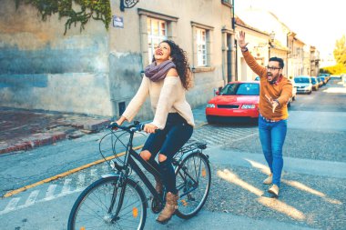 Mutlu çift şehirde güneşli bir sonbahar gününde bisiklet sürerken eğleniyor..