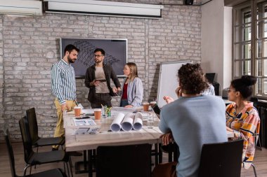 Modern iş adamlarından oluşan bir grup, yaratıcı ofiste mimari tasarımları tartışıyor..