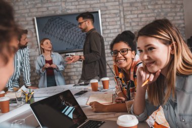 Modern iş adamlarından oluşan bir grup, yaratıcı ofiste mimari tasarımları tartışıyor..