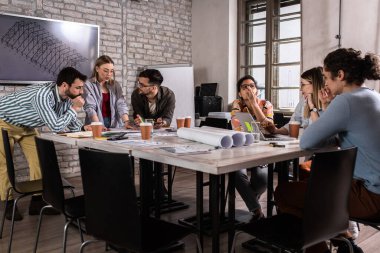 Modern iş adamlarından oluşan bir grup, yaratıcı ofiste mimari tasarımları tartışıyor..