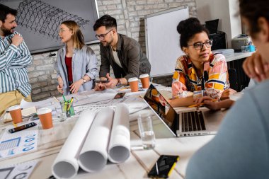 Modern iş adamlarından oluşan bir grup, yaratıcı ofiste mimari tasarımları tartışıyor..