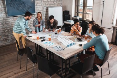 Modern iş adamlarından oluşan bir grup, yaratıcı ofiste mimari tasarımları tartışıyor..