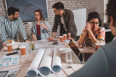 Modern iş adamlarından oluşan bir grup, yaratıcı ofiste mimari tasarımları tartışıyor..