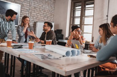 Modern iş adamlarından oluşan bir grup, yaratıcı ofiste mimari tasarımları tartışıyor..