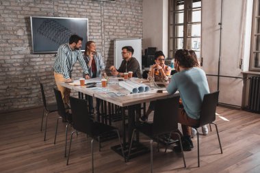 Modern iş adamlarından oluşan bir grup, yaratıcı ofiste mimari tasarımları tartışıyor..