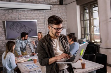 Kendine güvenen genç liderin portresi elinde dizüstü bilgisayarla ofiste duruyor..