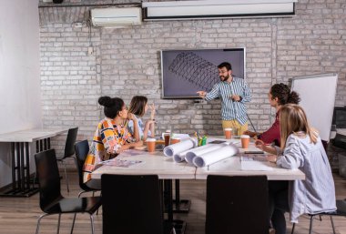 Modern iş adamlarından oluşan bir grup, yaratıcı ofiste mimari tasarımları tartışıyor..