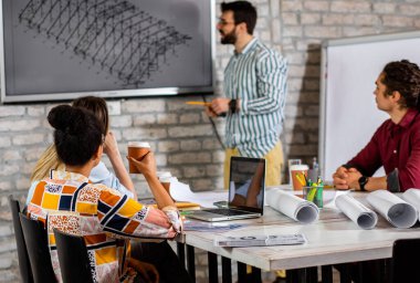 Modern iş adamlarından oluşan bir grup, yaratıcı ofiste mimari tasarımları tartışıyor..