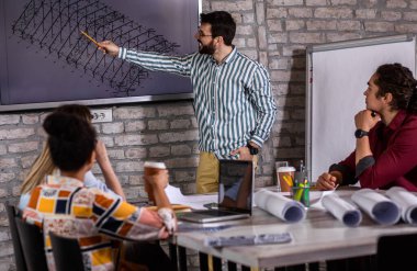 Modern iş adamlarından oluşan bir grup, yaratıcı ofiste mimari tasarımları tartışıyor..