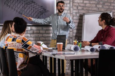 Modern iş adamlarından oluşan bir grup, yaratıcı ofiste mimari tasarımları tartışıyor..