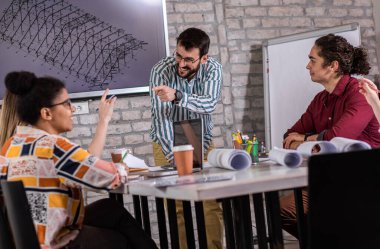 Modern iş adamlarından oluşan bir grup, yaratıcı ofiste mimari tasarımları tartışıyor..