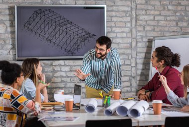 Modern iş adamlarından oluşan bir grup, yaratıcı ofiste mimari tasarımları tartışıyor..