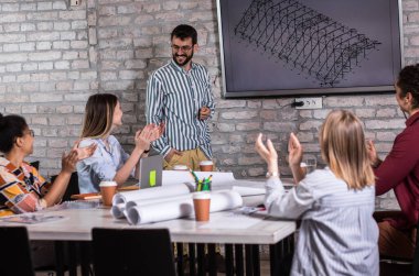 Modern iş adamlarından oluşan bir grup, yaratıcı ofiste mimari tasarımları tartışıyor..