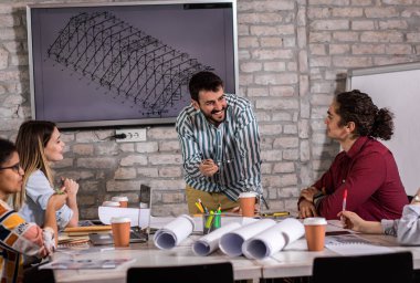 Modern iş adamlarından oluşan bir grup, yaratıcı ofiste mimari tasarımları tartışıyor..