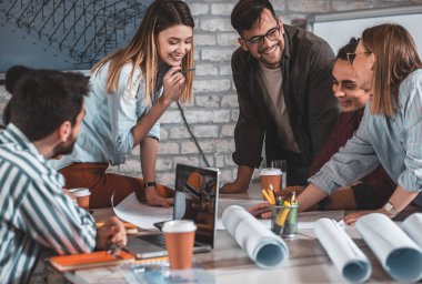 Modern iş adamlarından oluşan bir grup, yaratıcı ofiste mimari tasarımları tartışıyor..