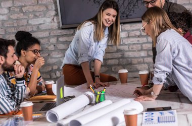 Modern iş adamlarından oluşan bir grup, yaratıcı ofiste mimari tasarımları tartışıyor..