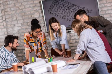 Modern iş adamlarından oluşan bir grup, yaratıcı ofiste mimari tasarımları tartışıyor..