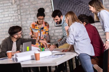 Modern iş adamlarından oluşan bir grup, yaratıcı ofiste mimari tasarımları tartışıyor..