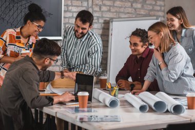 Modern iş adamlarından oluşan bir grup, yaratıcı ofiste mimari tasarımları tartışıyor..