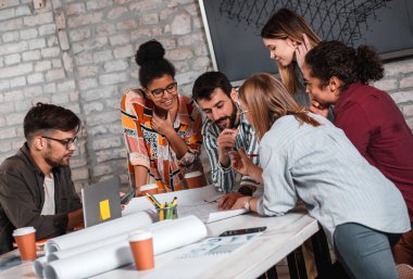 Modern iş adamlarından oluşan bir grup, yaratıcı ofiste mimari tasarımları tartışıyor..