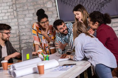 Modern iş adamlarından oluşan bir grup, yaratıcı ofiste mimari tasarımları tartışıyor..