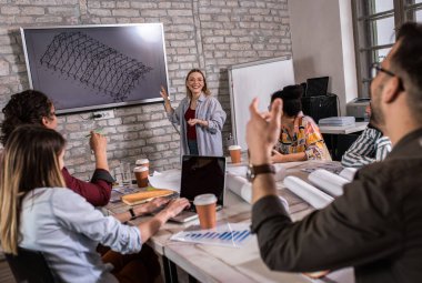 Modern iş adamlarından oluşan bir grup, yaratıcı ofiste mimari tasarımları tartışıyor..