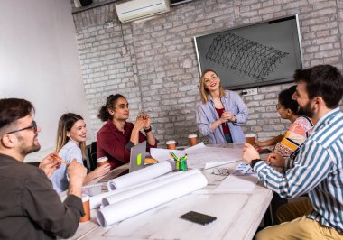 Modern iş adamlarından oluşan bir grup, yaratıcı ofiste mimari tasarımları tartışıyor..