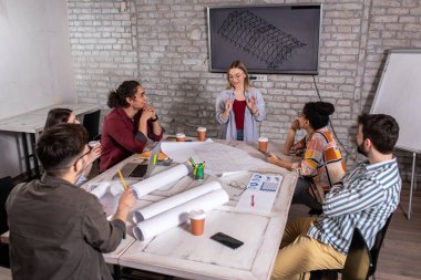 Modern iş adamlarından oluşan bir grup, yaratıcı ofiste mimari tasarımları tartışıyor..