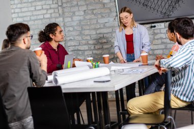 Modern iş adamlarından oluşan bir grup, yaratıcı ofiste mimari tasarımları tartışıyor..