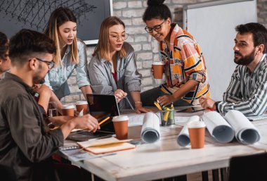 Modern iş adamlarından oluşan bir grup, yaratıcı ofiste mimari tasarımları tartışıyor..