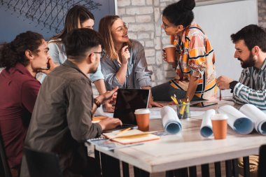 Modern iş adamlarından oluşan bir grup, yaratıcı ofiste mimari tasarımları tartışıyor..