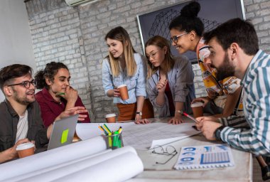 Modern iş adamlarından oluşan bir grup, yaratıcı ofiste mimari tasarımları tartışıyor..