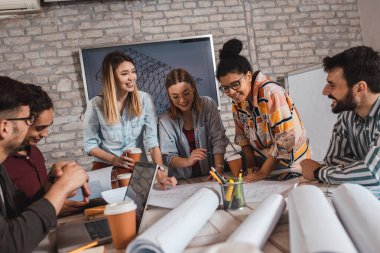 Modern iş adamlarından oluşan bir grup, yaratıcı ofiste mimari tasarımları tartışıyor..