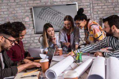 Modern iş adamlarından oluşan bir grup, yaratıcı ofiste mimari tasarımları tartışıyor..