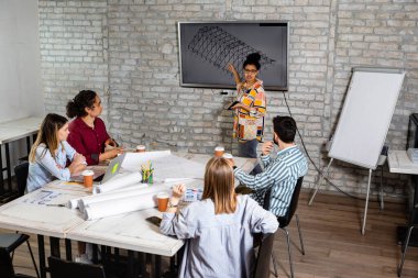 Modern iş adamlarından oluşan bir grup, yaratıcı ofiste mimari tasarımları tartışıyor..