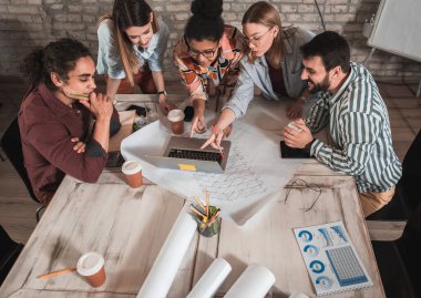 Modern iş adamlarından oluşan bir grup, yaratıcı ofiste mimari tasarımları tartışıyor..