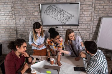 Modern iş adamlarından oluşan bir grup, yaratıcı ofiste mimari tasarımları tartışıyor..