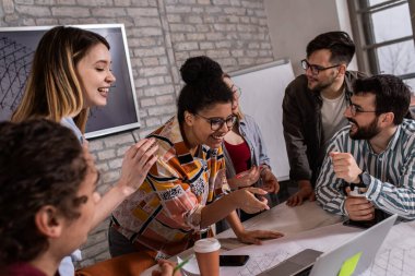 Modern iş adamlarından oluşan bir grup, yaratıcı ofiste mimari tasarımları tartışıyor..