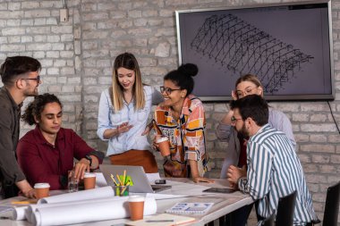 Modern iş adamlarından oluşan bir grup, yaratıcı ofiste mimari tasarımları tartışıyor..