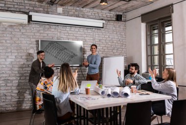 Modern iş adamlarından oluşan bir grup, yaratıcı ofiste mimari tasarımları tartışıyor..