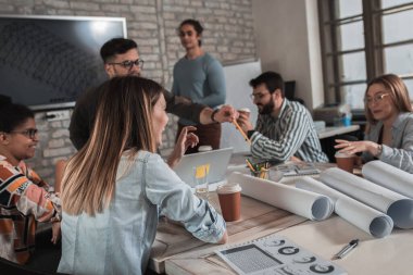 Modern iş adamlarından oluşan bir grup, yaratıcı ofiste mimari tasarımları tartışıyor..