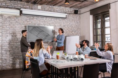 Modern iş adamlarından oluşan bir grup, yaratıcı ofiste mimari tasarımları tartışıyor..