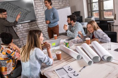 Modern iş adamlarından oluşan bir grup, yaratıcı ofiste mimari tasarımları tartışıyor..