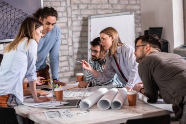 Modern iş adamlarından oluşan bir grup, yaratıcı ofiste mimari tasarımları tartışıyor..