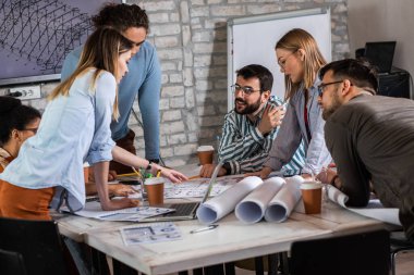 Modern iş adamlarından oluşan bir grup, yaratıcı ofiste mimari tasarımları tartışıyor..
