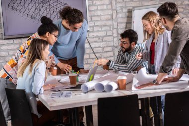 Modern iş adamlarından oluşan bir grup, yaratıcı ofiste mimari tasarımları tartışıyor..