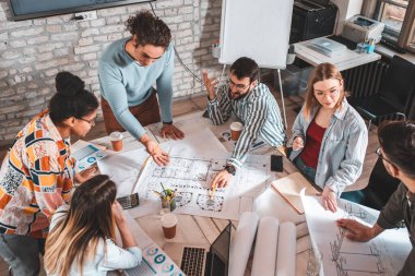 Modern iş adamlarından oluşan bir grup, yaratıcı ofiste mimari tasarımları tartışıyor..